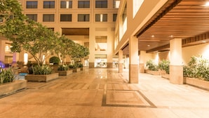 A spacious indoor courtyard with tiled flooring, potted plants, and a covered walkway. - Jaipur Marriott Hotel (Jaipur)