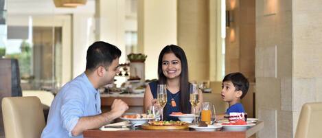 Una familia cenando en una mesa con diferentes platos y bebidas.