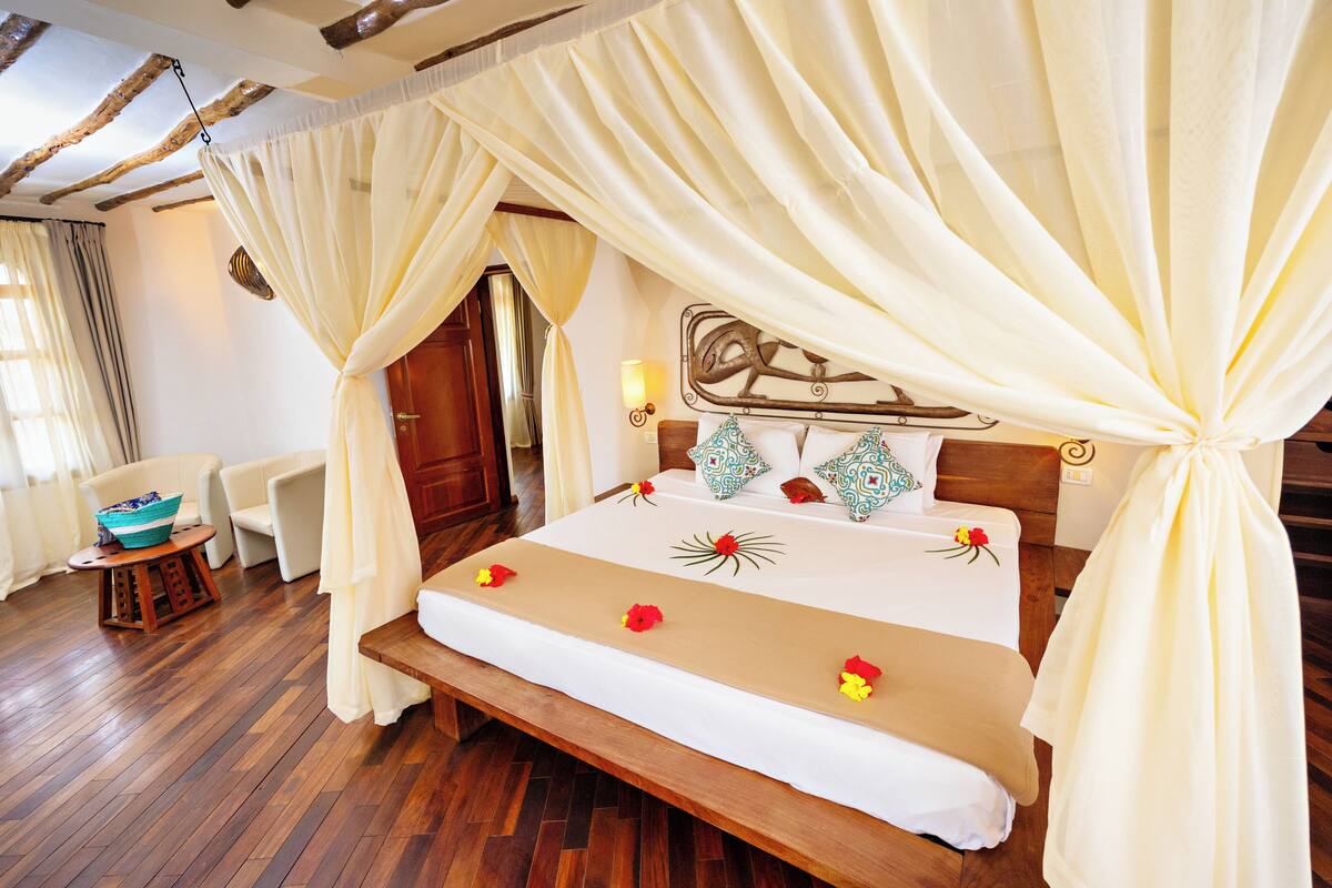 A bed with a canopy, a wooden headboard, and a bedside table with a lamp.