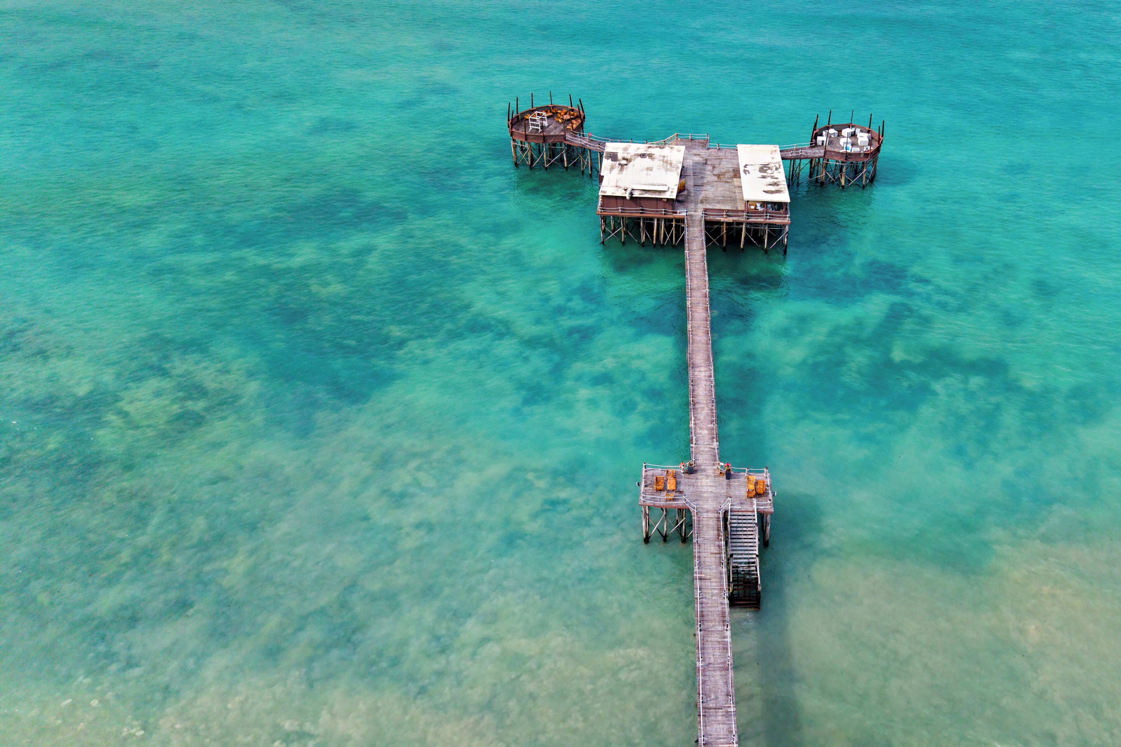 An aerial view of a pier with multiple platforms extending into turquoise water.