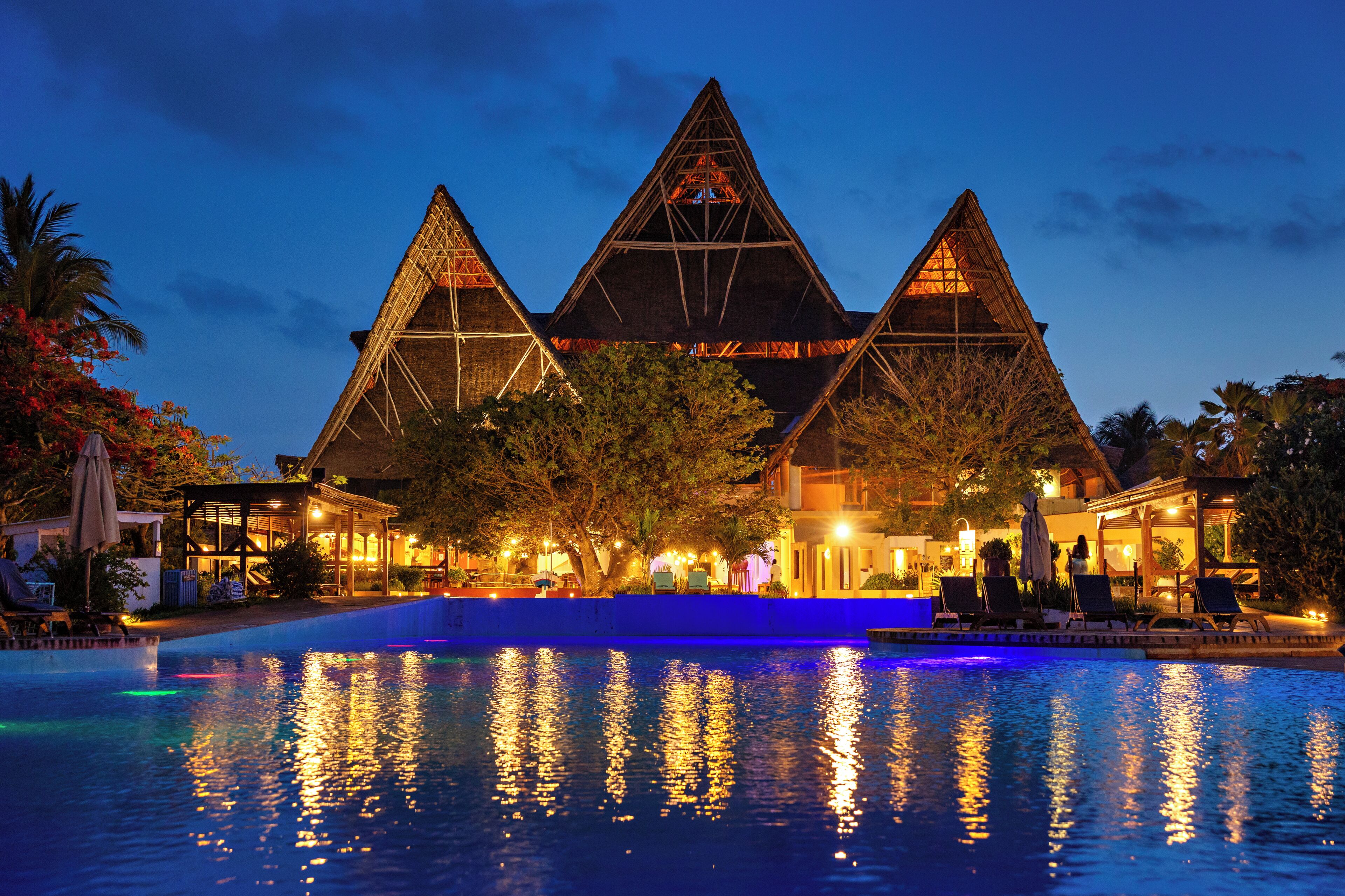 A hotel with a pool, triangular architecture, and outdoor seating.