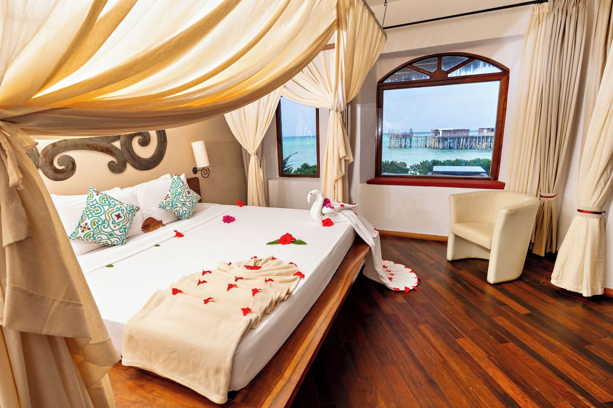 A room with a bed, a chair, a window with a view, and curtains.