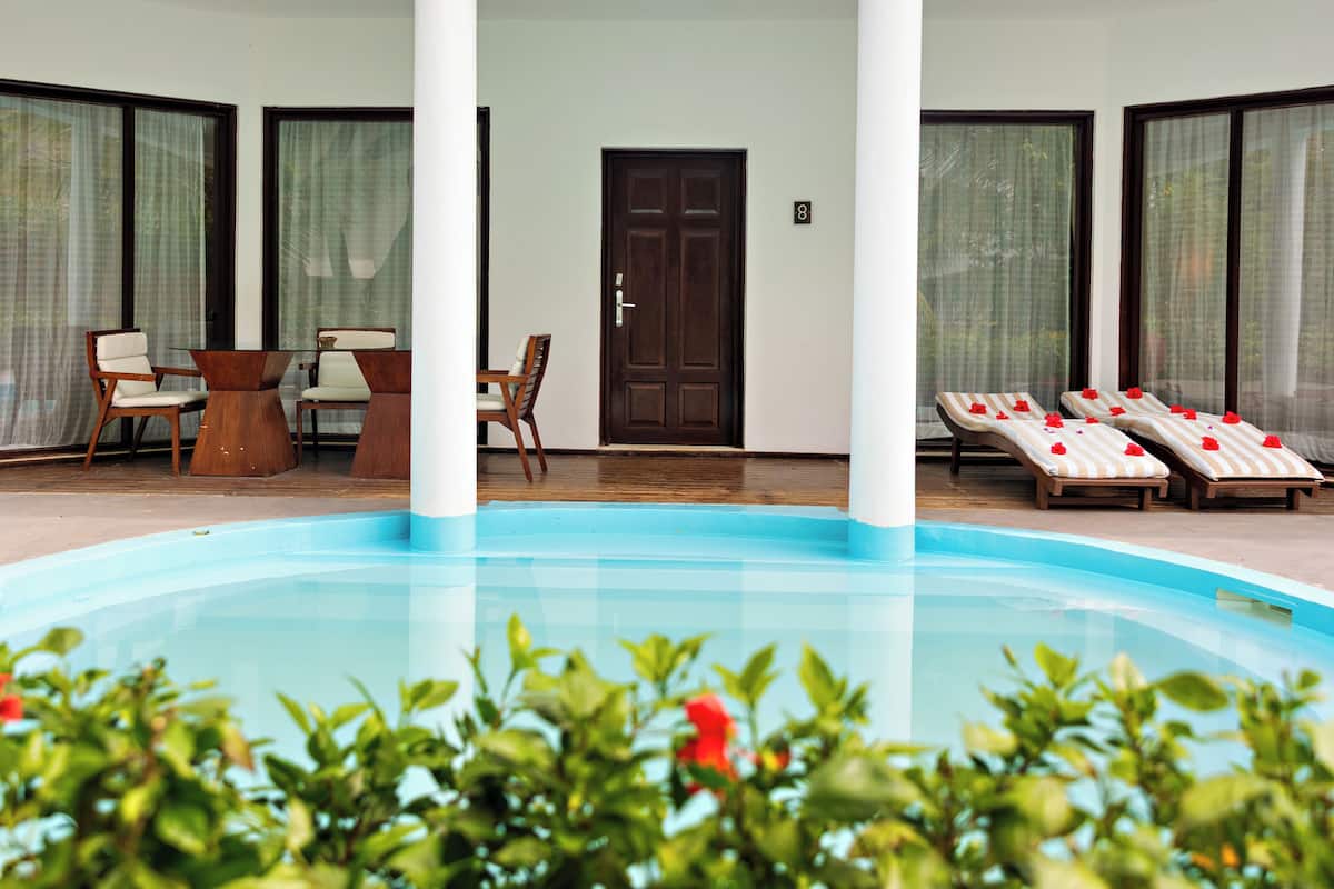 A pool area with lounge chairs, a table, and chairs.