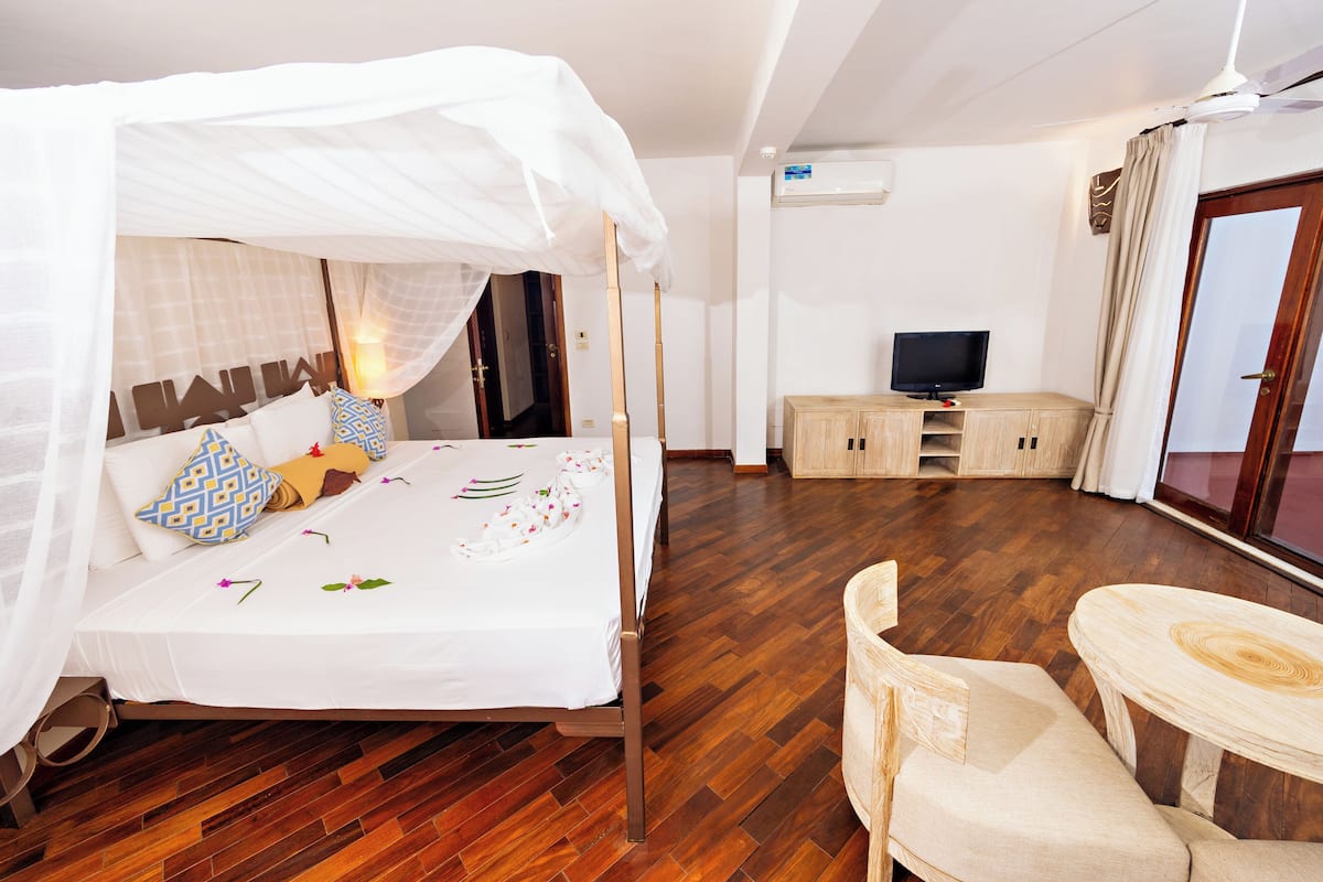 A hotel room with a bed, a TV, a wooden cabinet, a chair, and a table.