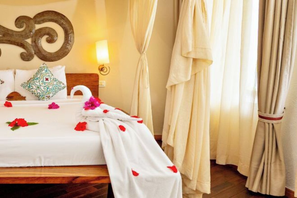 A neatly made bed with a white bedspread, decorative pillows, and a towel draped over the side.