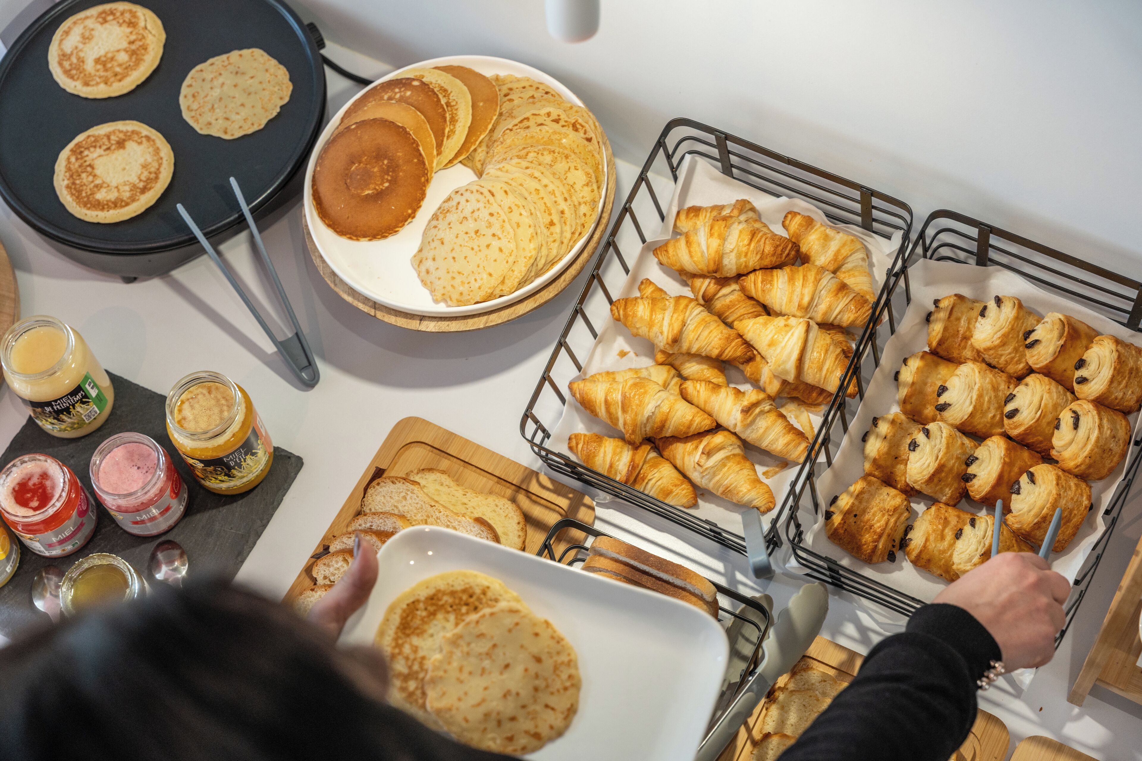 En frukostbuffé med pannkakor, croissanter och olika sorters pålägg.