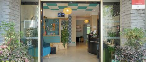 The entrance of Grand Hotel with a reception desk, check-in area, and potted plants.