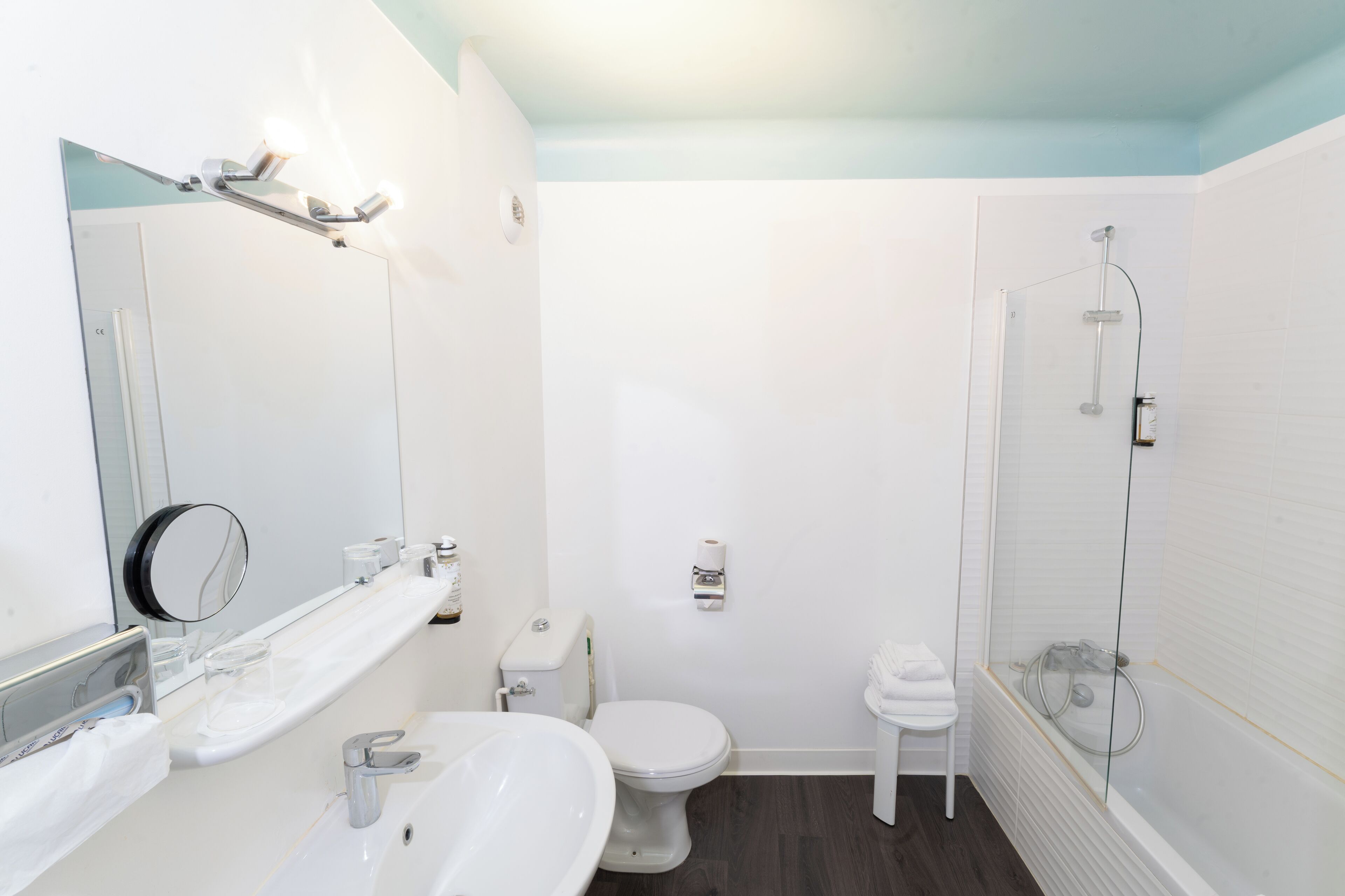 A modern bathroom with a white sink, mirror, toilet, and shower.