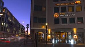 Entrada de un hotel con un cartel que dice "Ulms flüssiges Gold Hotel Goldenes Rad" y una calificación de tres estrellas.