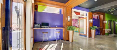A modern lobby with a reception desk, bar stools, and a large potted plant.