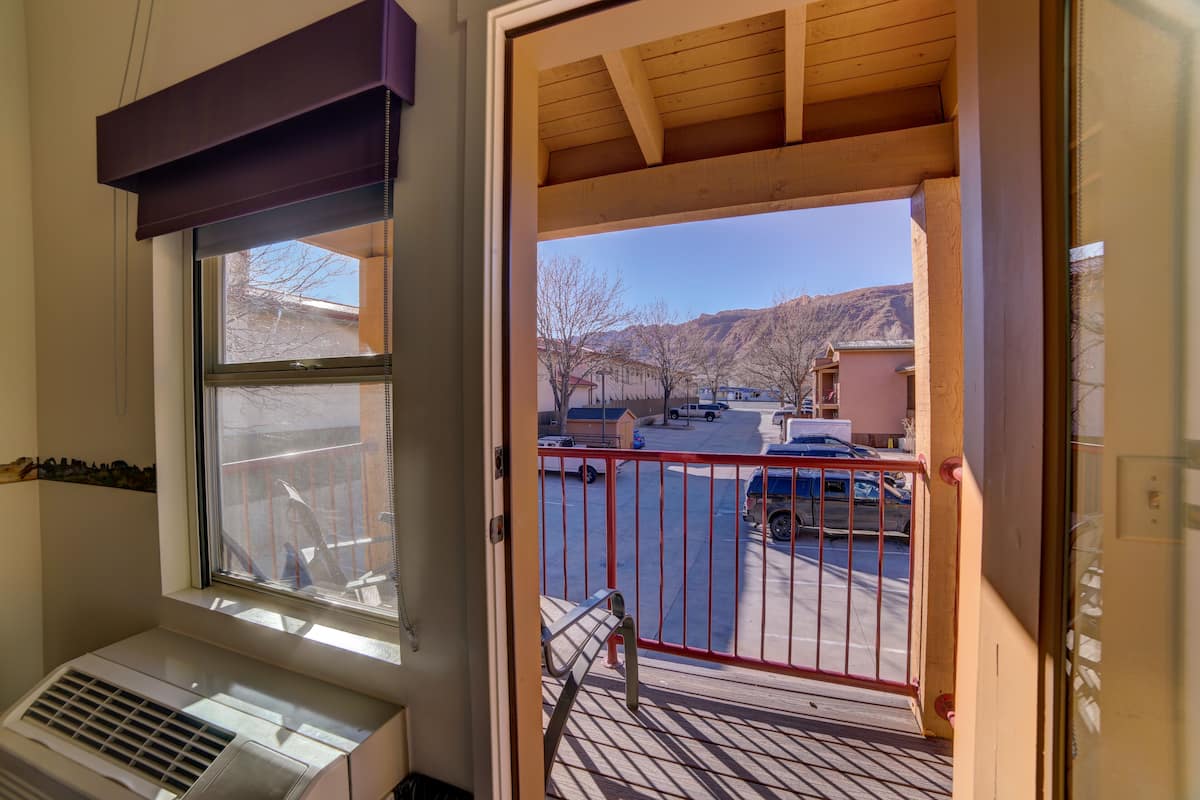 A room with a large window, a radiator, and a view of a parking lot and mountains.
