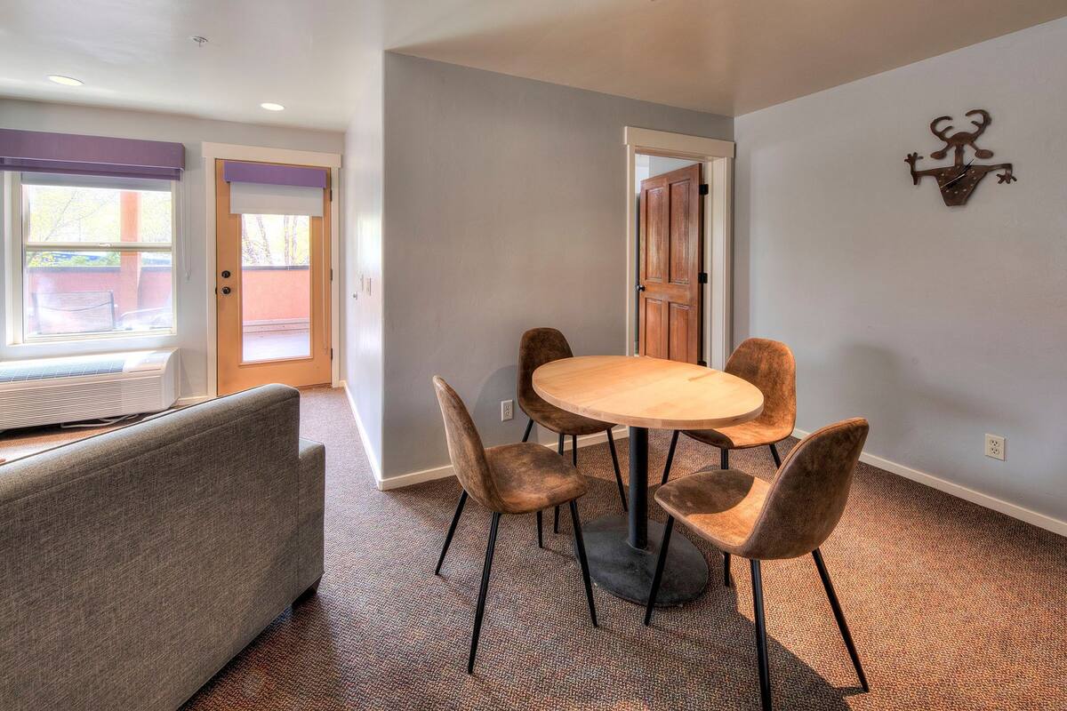 A dining area with a round table and four chairs, a bench, and a wall-mounted decoration.