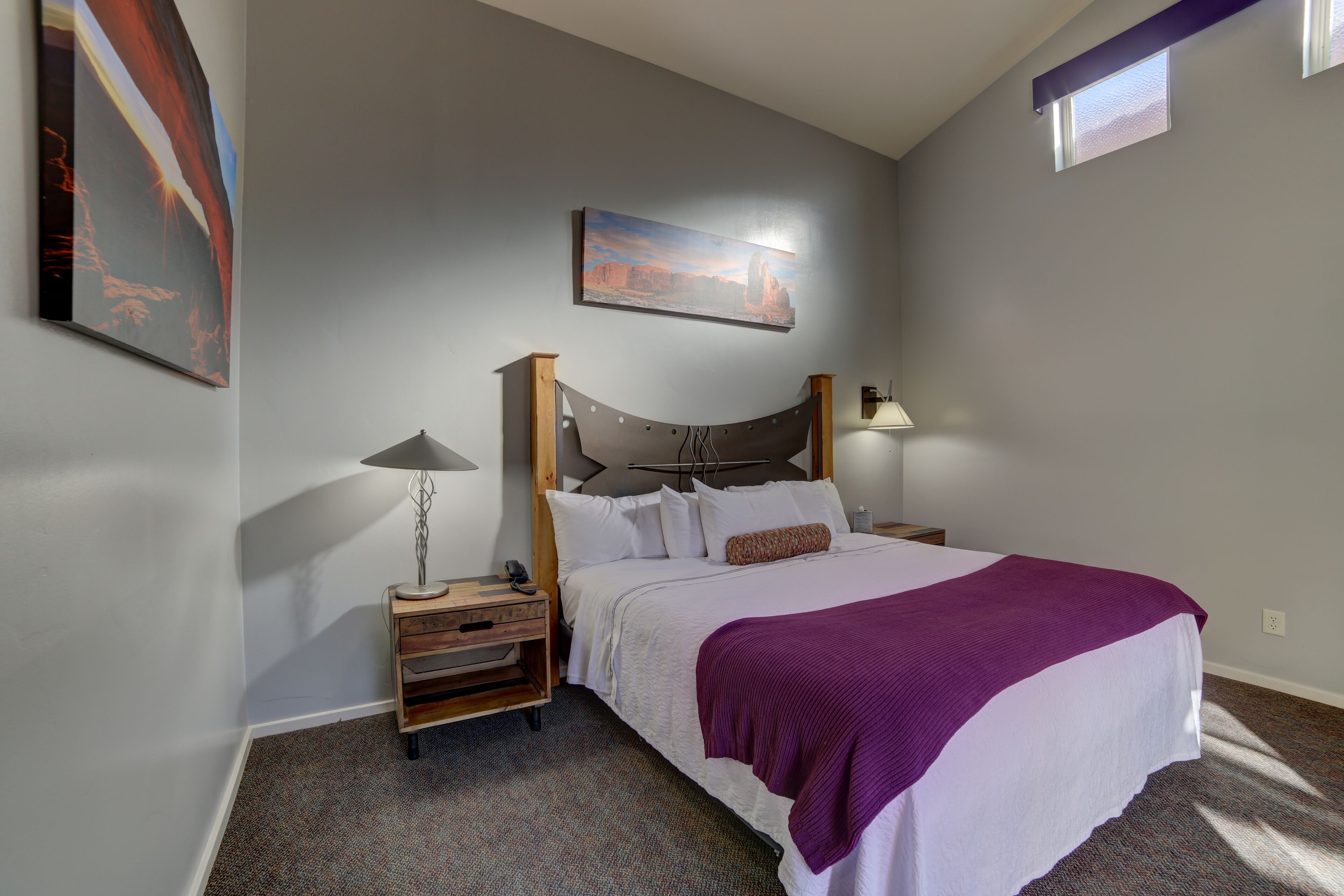 A bedroom with a bed, a nightstand, a lamp, and a painting on the wall.
