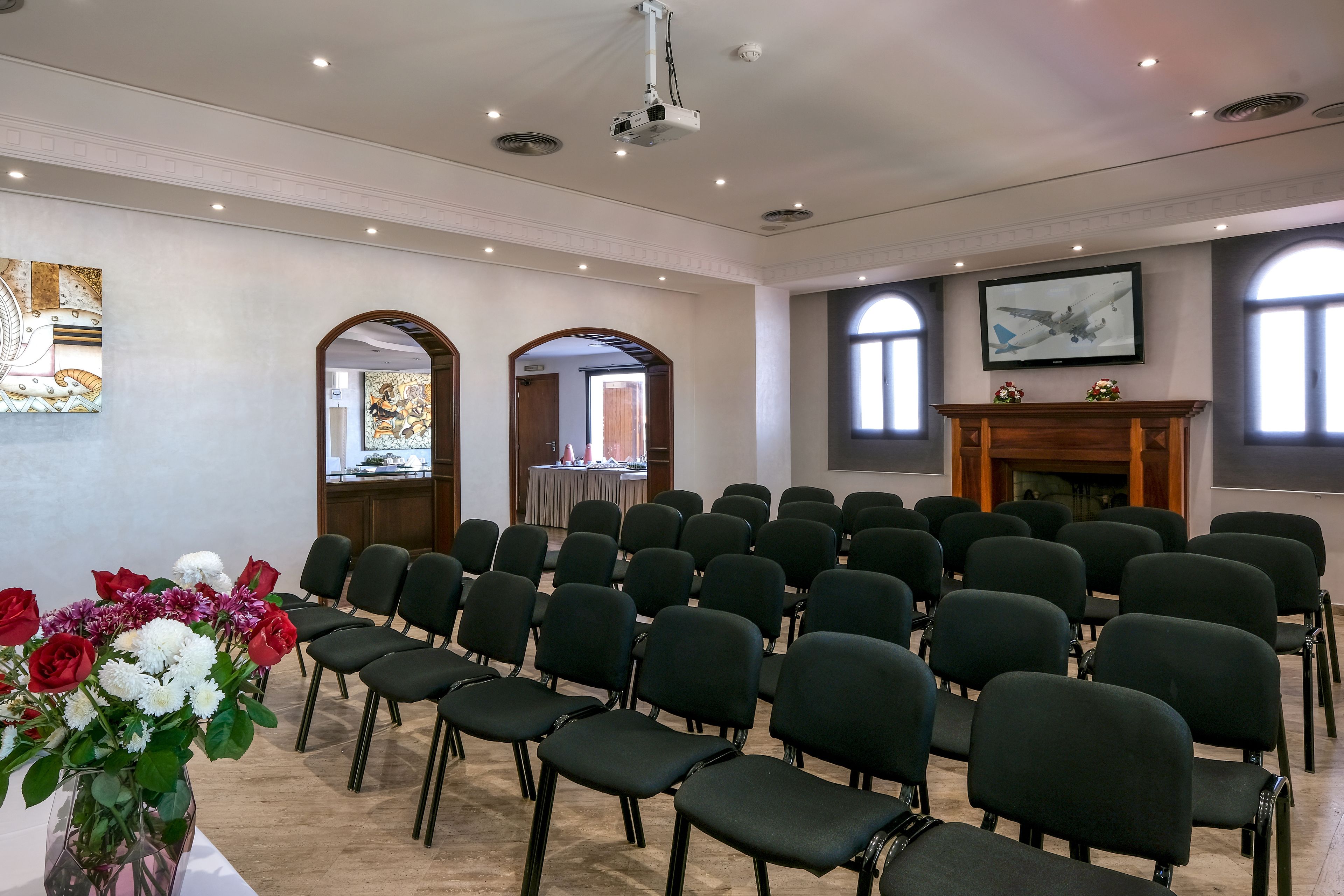 A conference room with rows of black chairs, a projector, and a fireplace.