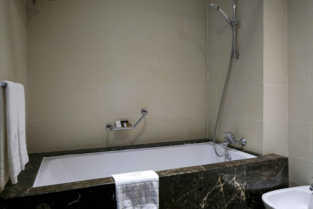 A bathroom with a bathtub, a shower, a sink, and a towel rack.