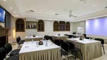 A conference room with multiple tables, chairs, and presentation screens.