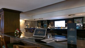 A bar area with a laptop, a glass of water, and a menu stand. - Hotel Belere Rabat (Rabat)