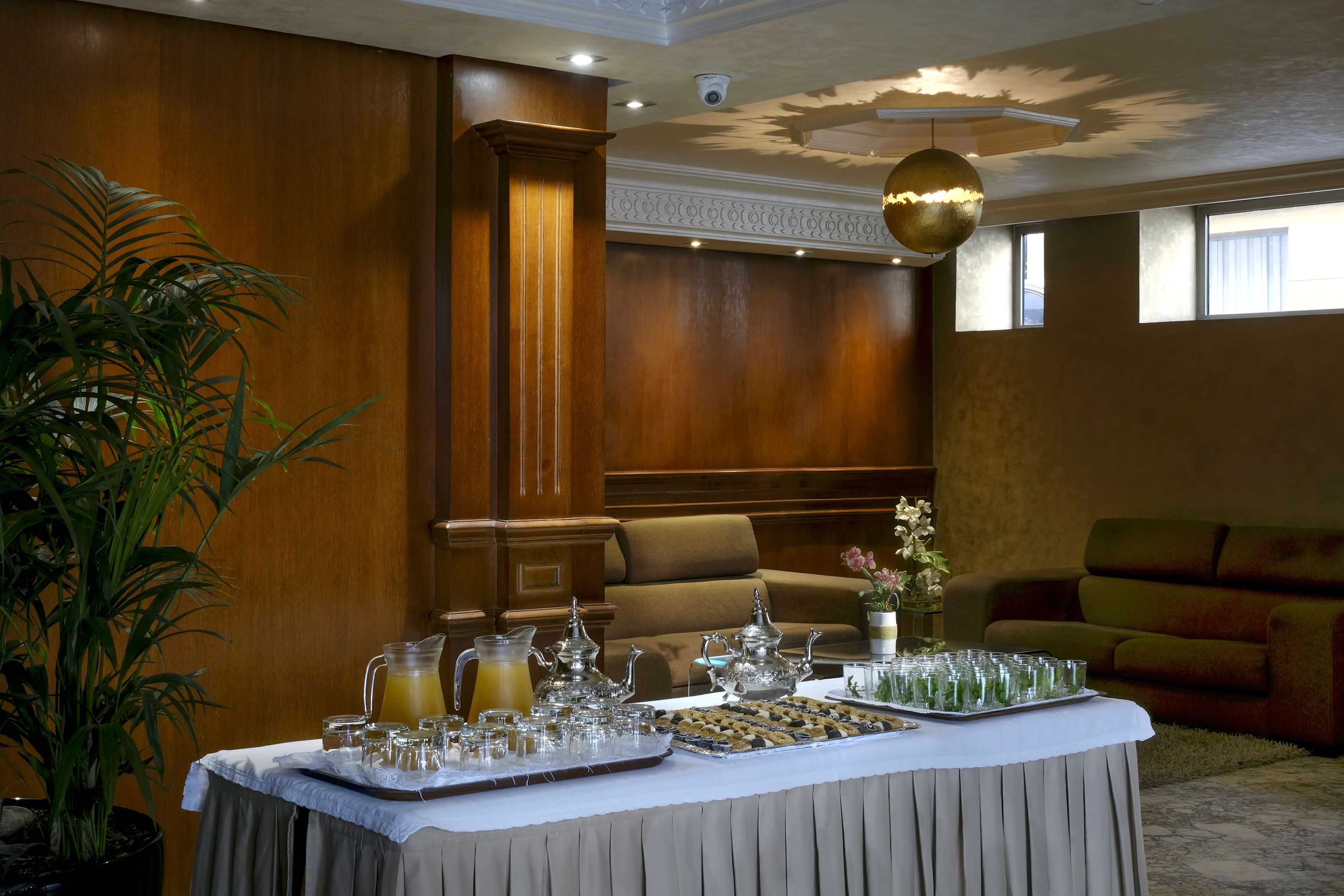 Une table de buffet garnie de divers plats et boissons, une plante en pot et un canapé en arrière-plan.