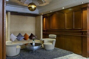 Un hall con un conjunto de sofás, dos sillones, una mesa redonda de centro y un jarrón decorativo.