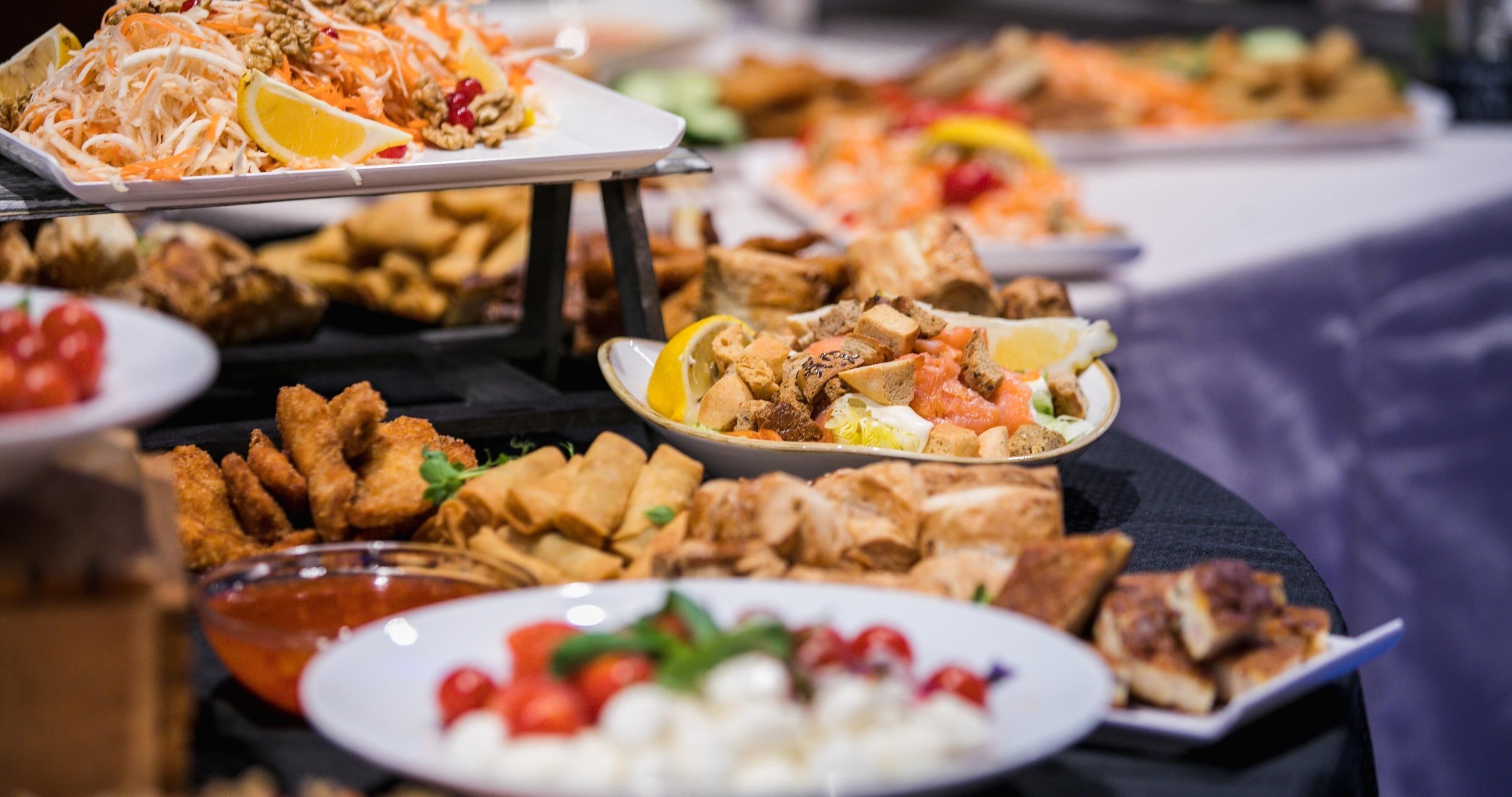 Un buffet con diversi piatti, tra cui cibi fritti, insalate e salse.