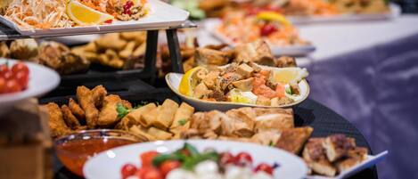 Un buffet con diversi piatti, tra cui cibi fritti, insalate e salse.