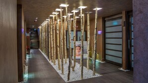 A hallway with a row of birch trees, a staircase, and a reception area with a poster. - Alpin Resort Hotel (Brasov)