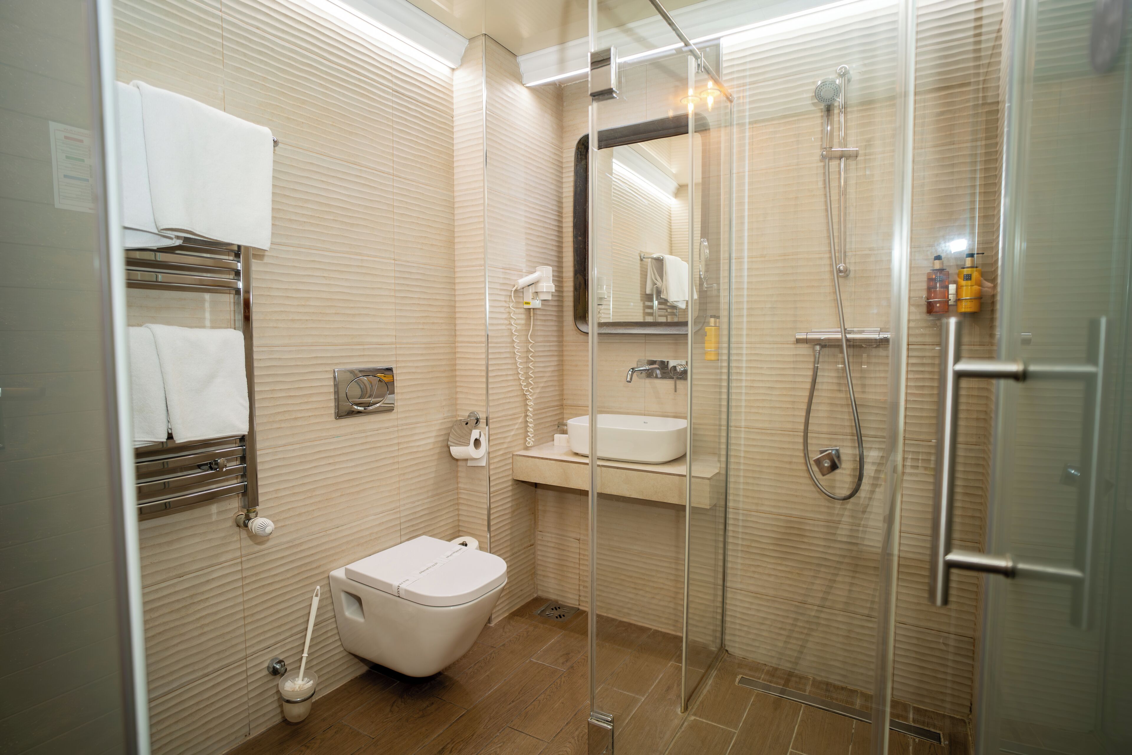 A modern bathroom with a glass-enclosed shower, a toilet, a sink, and a towel rack.