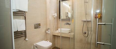 Un baño moderno con ducha envuelta en vidrio, inodoro, lavamanos y toallero.