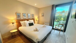 A hotel room with a large bed, bedside lamps, a small table, and a view of the outdoors. - Best Western Hotel de la plage Normandie (Asnelles)