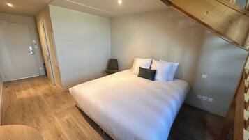 Une chambre à coucher avec un grand lit, une chaise, un banc en bois et une porte.