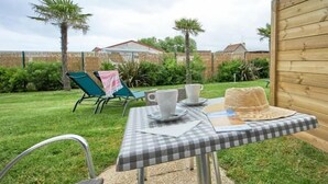 A checkered table with cups and a hat, surrounded by a wooden fence and greenery. - Best Western Hotel de la plage Normandie (Asnelles)