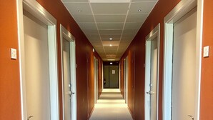 A hotel hallway with doors on both sides, a carpeted floor, and a ceiling with recessed lighting. - Best Western Hotel de la plage Normandie (Asnelles)