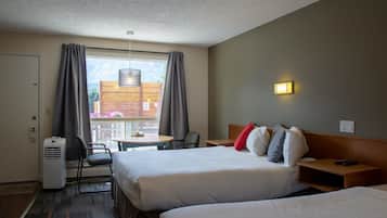 A hotel room with two beds, a desk, a chair, a table, and a window with curtains.