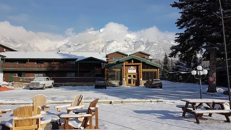 A lodge with a wooden exterior and a snow-covered mountain backdrop.
