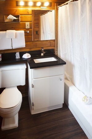 A compact bathroom with a toilet, sink, and shower area.