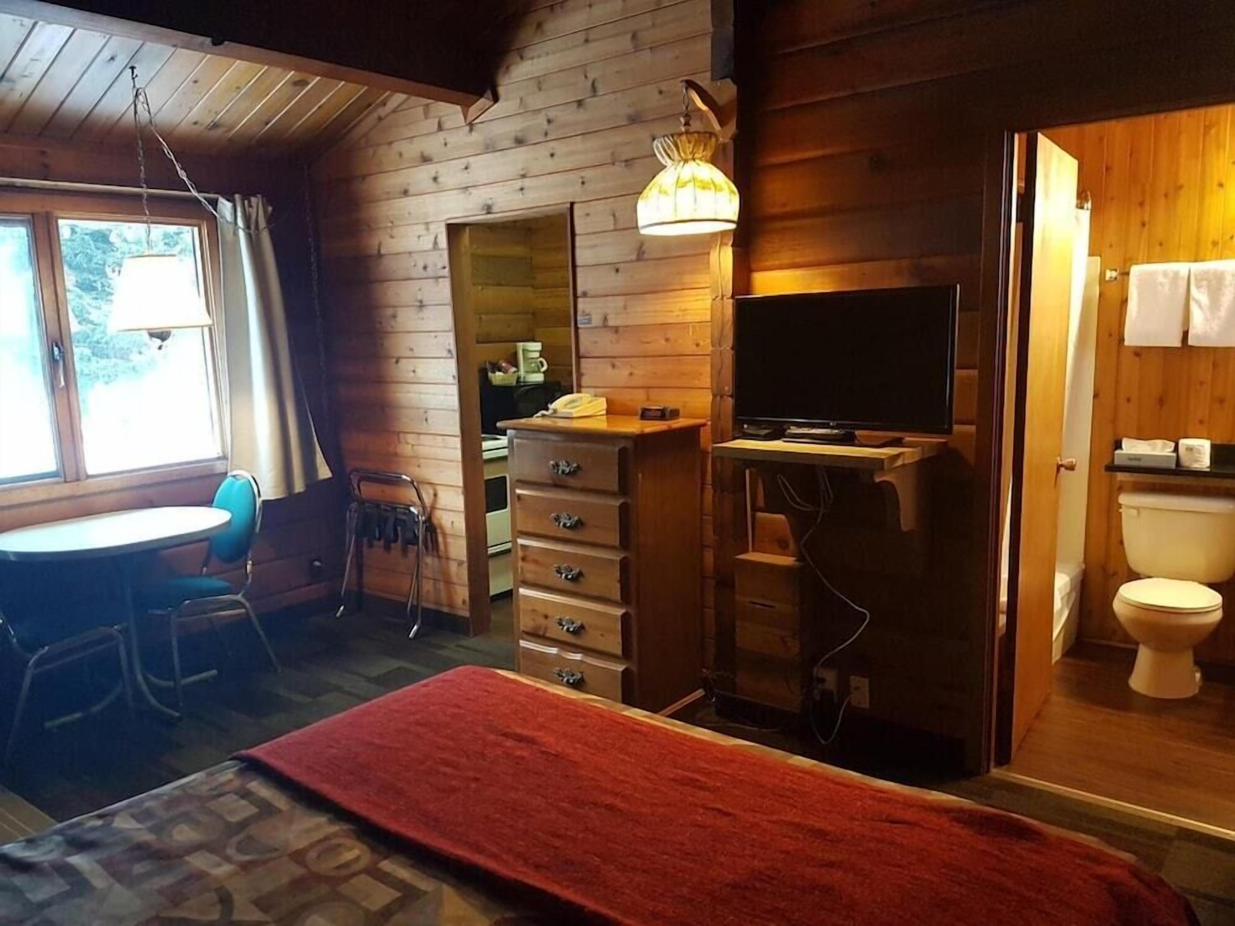 Una habitación acogedora con cama, escritorio, silla, televisión y baño.
