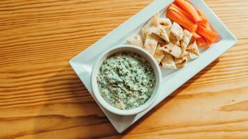 A white plate with a bowl of dip and carrot sticks on a wooden table.