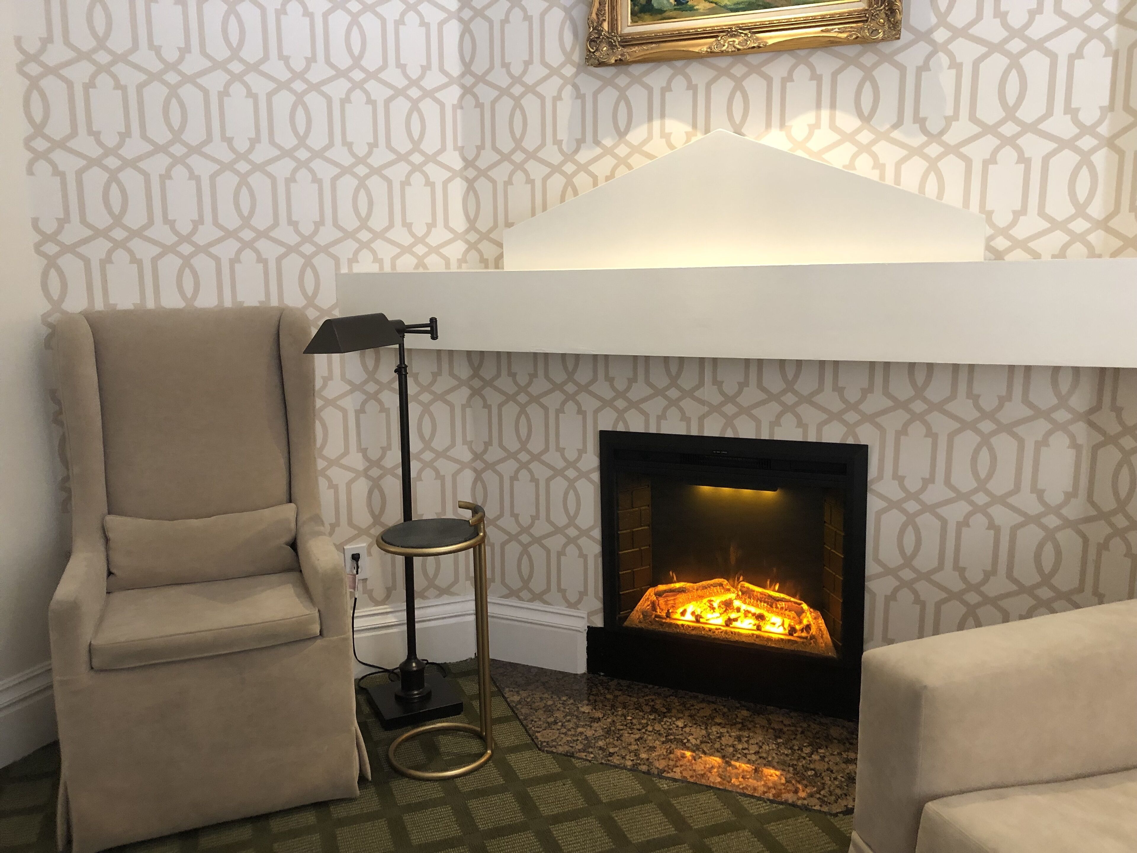 A cozy living room with a fireplace, a tall floor lamp, and a comfortable armchair.