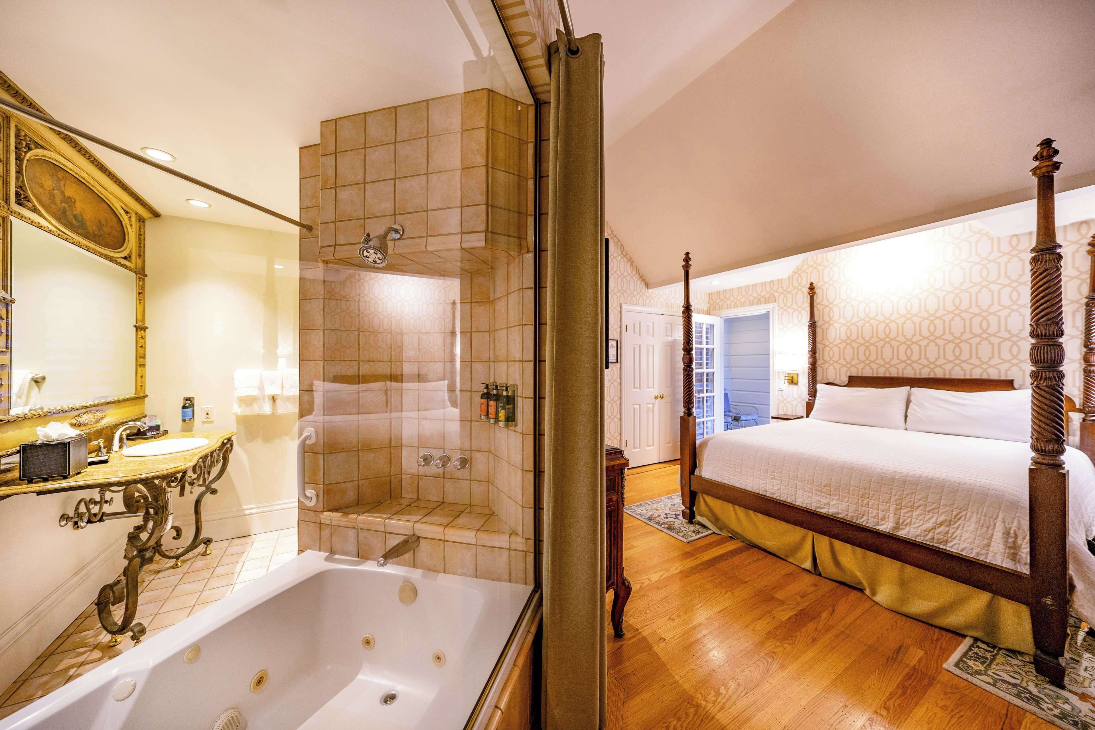 A spacious bedroom with a large bed, a separate bathroom with a bathtub, and a shower.