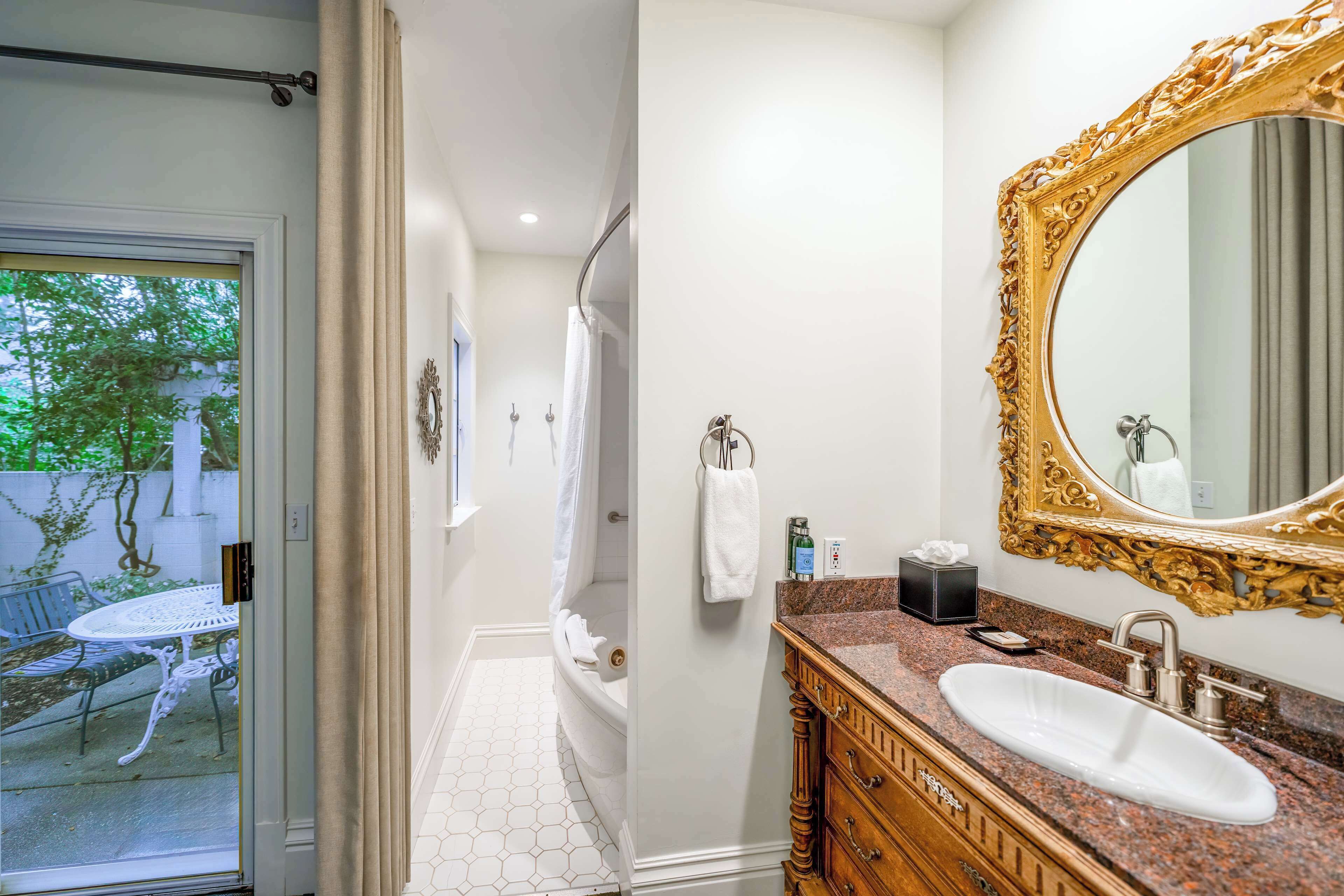 Un bagno con lavandino bianco, mobile contenitore in legno e uno specchio grande e decorativo.