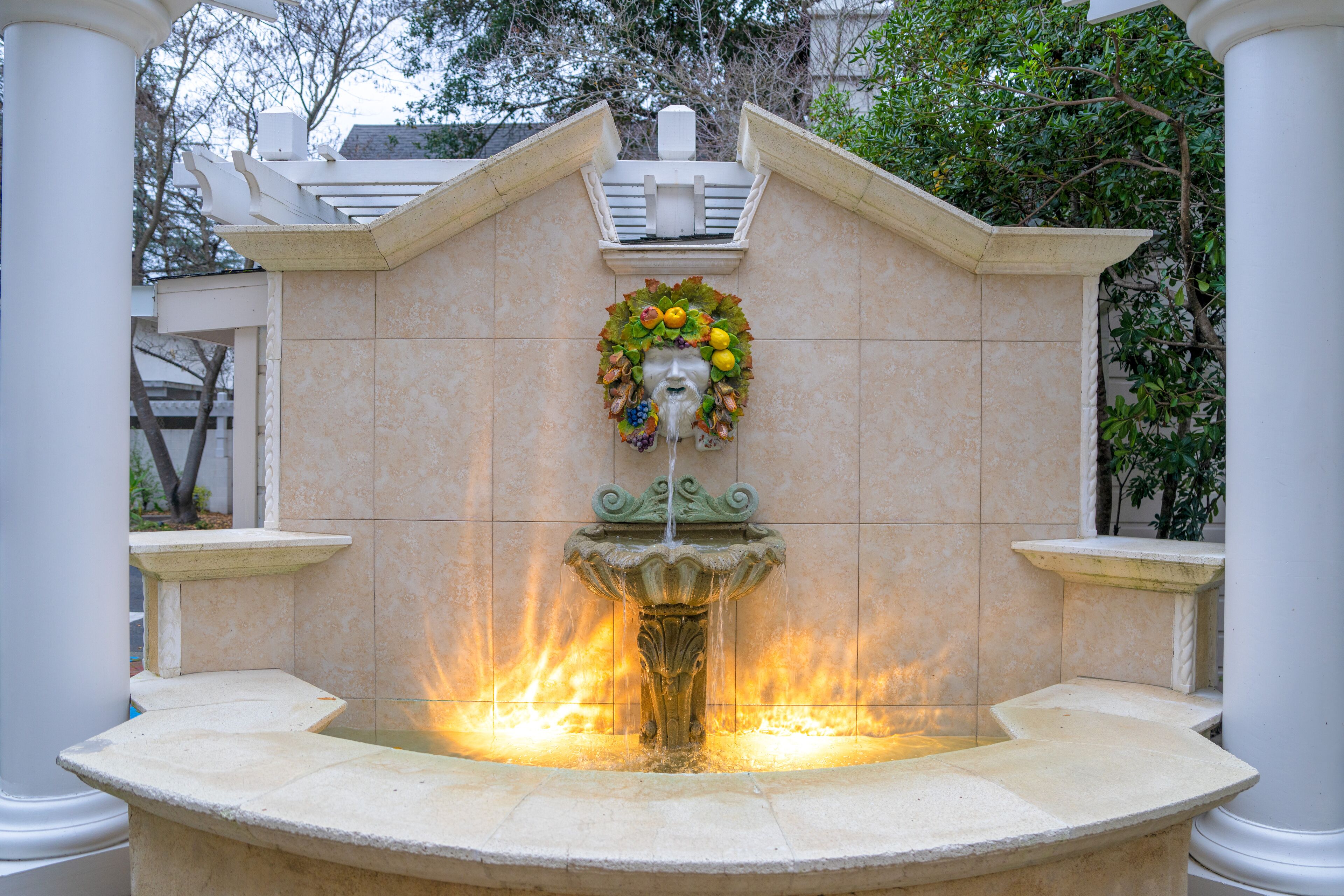 A fountain with a decorative headpiece and water spouting from the center.
