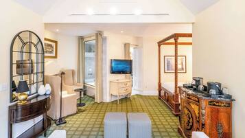 A hotel room with a green patterned floor, a large mirror, a sofa, a TV, and a wooden cabinet.
