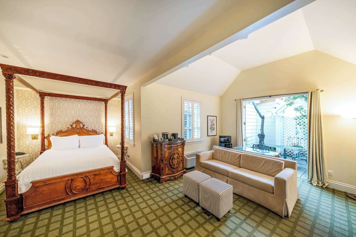 A bedroom with a four-poster bed, a sofa, and a small table.