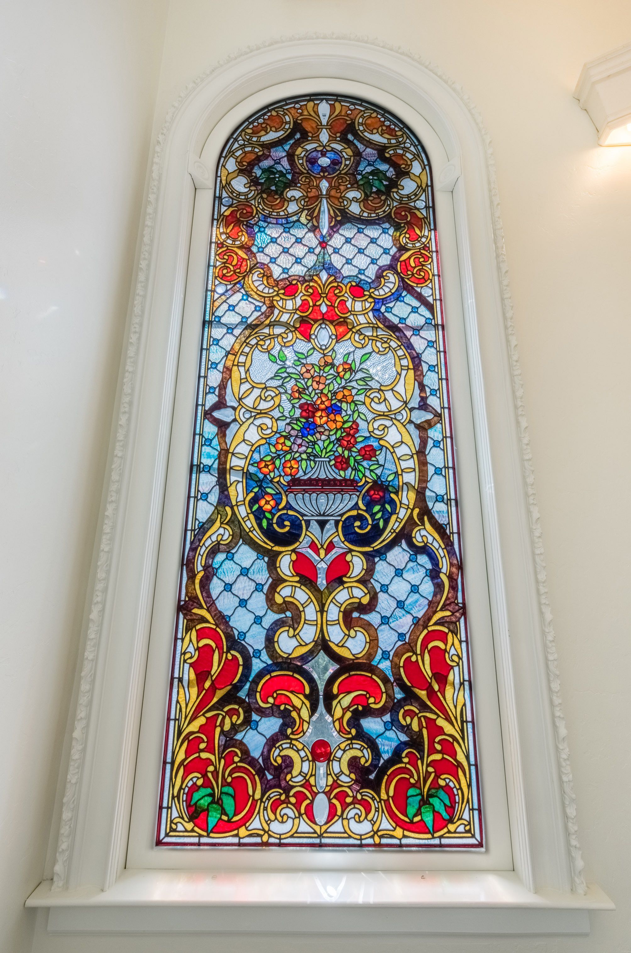 Une vitre décorative en verre coloré, ornée de motifs floraux et géométriques complexes.