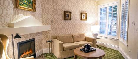 A living room with a fireplace, a sofa, a coffee table, and patterned wallpaper.