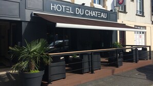 Ein Hotel namens "HOTEL DU CHATEAU" mit Außenbestuhlung und einem Blumentopf.