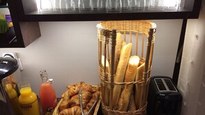 Ein Frühstücksbuffet mit Croissants, Baguettes, Saft und einem Toaster.