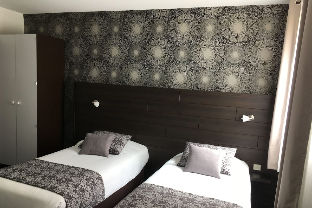 Ein Hotelzimmer mit zwei Betten, einem Kleiderschrank und einem gemusterten Kopfteil.