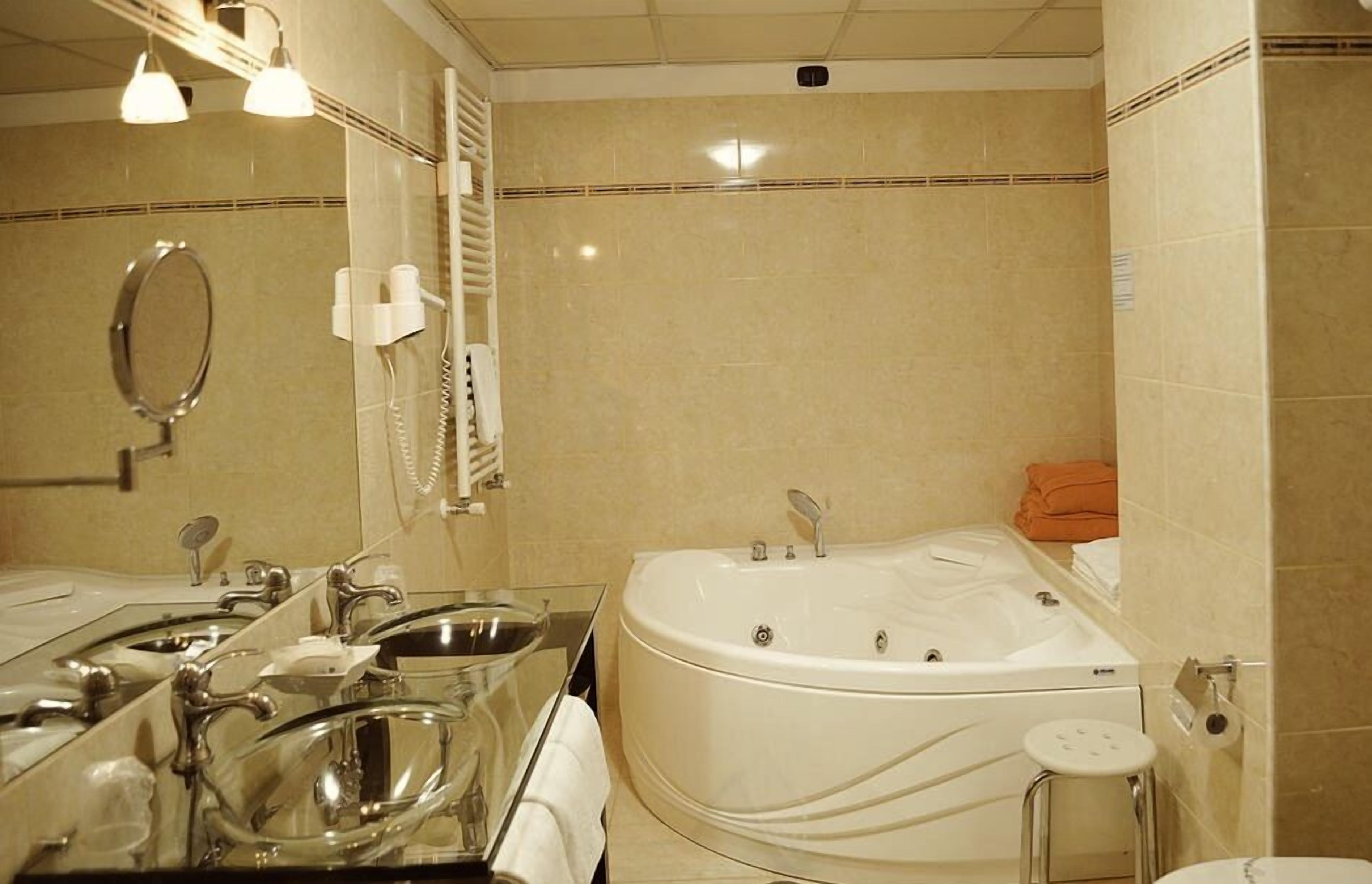 Ein Badezimmer mit einer großen Badewanne, zwei Waschbecken, einem Spiegel und einer Toilette.