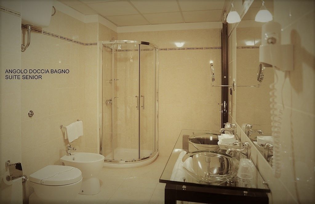Une salle de bain avec une douche à parois de verre, un lavabo avec un miroir et des toilettes.